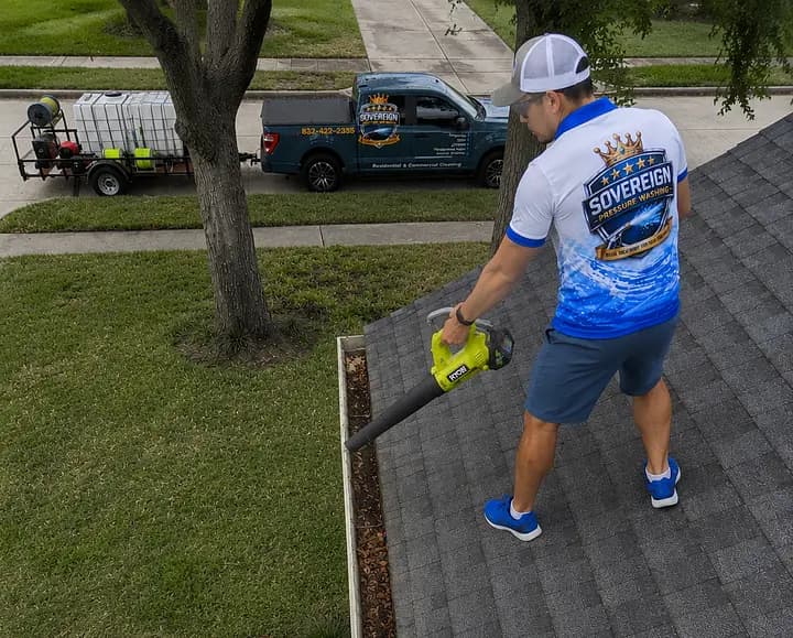 Technician clearing debris from a roof gutter